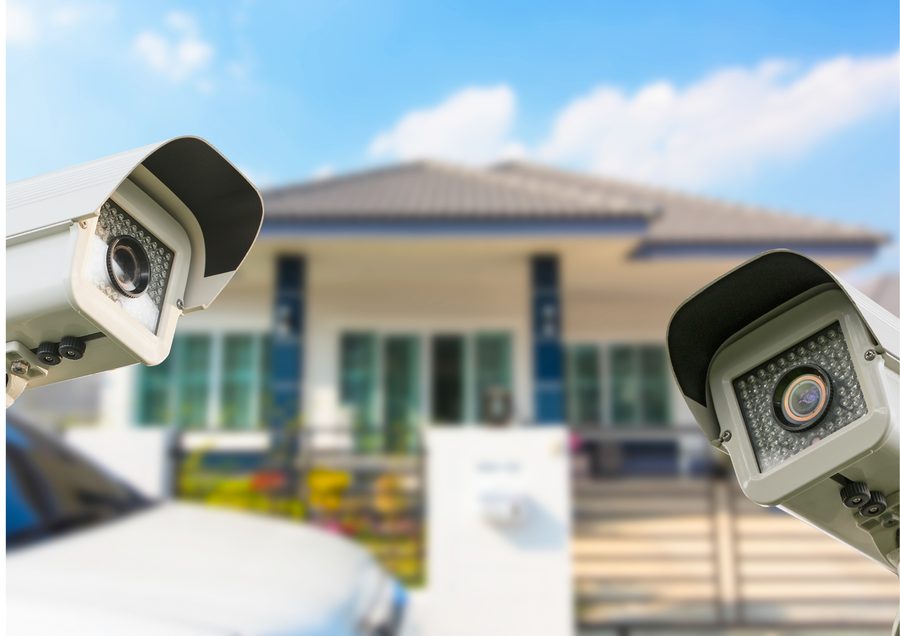 Two outdoor security cameras covering the approach to a house